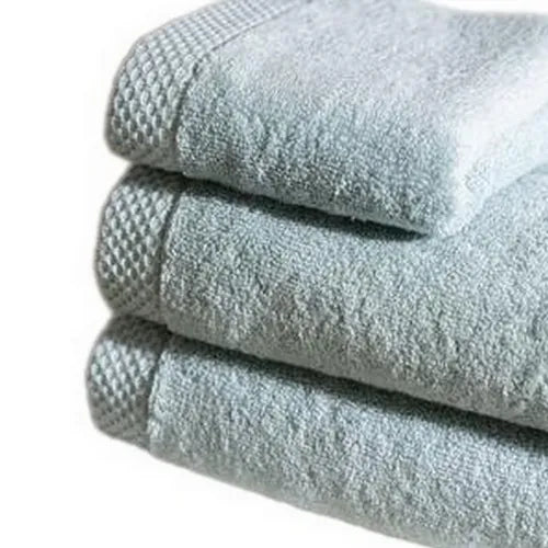 Set van drie opgevouwen luxe handdoeken in zacht grijs op een witte achtergrond.