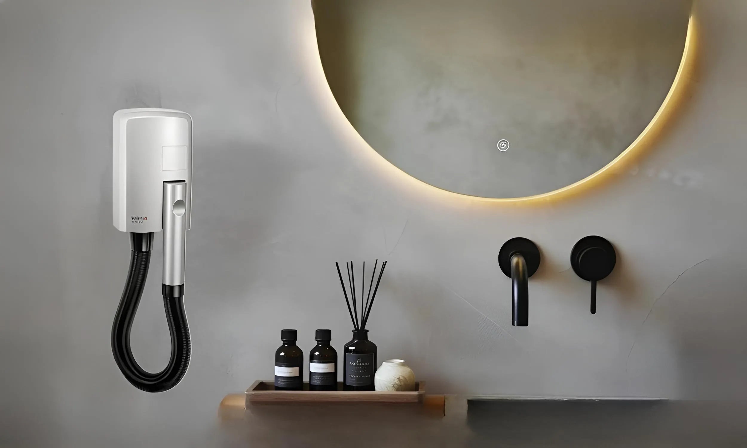 Witte wandhaardroger Hotello in badkamer met betonnen muur, naast spiegel met lichtrand, zwarte kranen en potjes op het blad